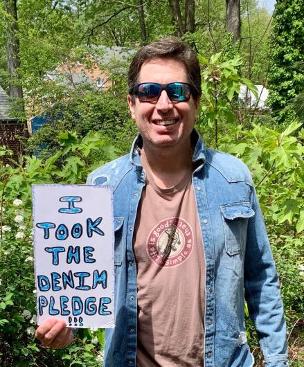 Ray Limon from OS-OHC outside, holding a hand written in blue words, I took the Pledge #DenimDay sign.