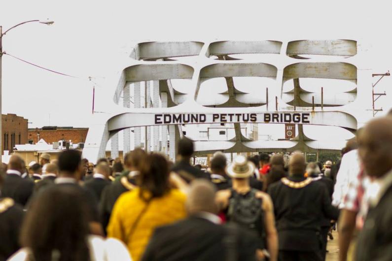 Selma to Montgomery National Historic Trail Photo of a large group of people walking across the historic Edmund Pettus Bridge in Selma, Alabama.