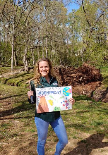 Tina Roberts-Ashby from USGS outdoors holding an I took the pledge sign with colorful drawings 