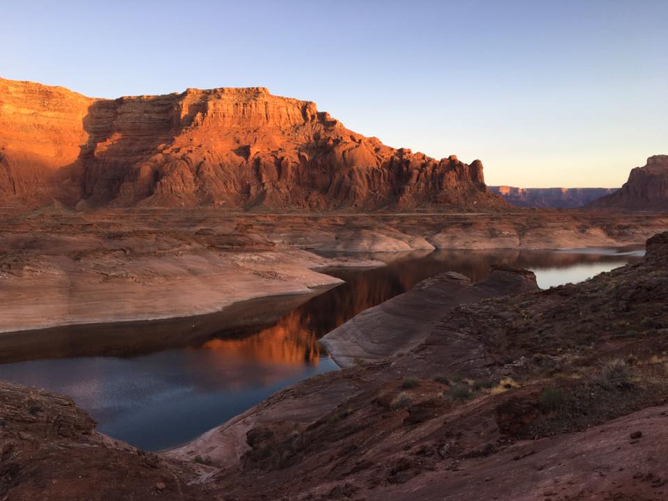 Water flows through tall orange rock features catching rays of sunshine.