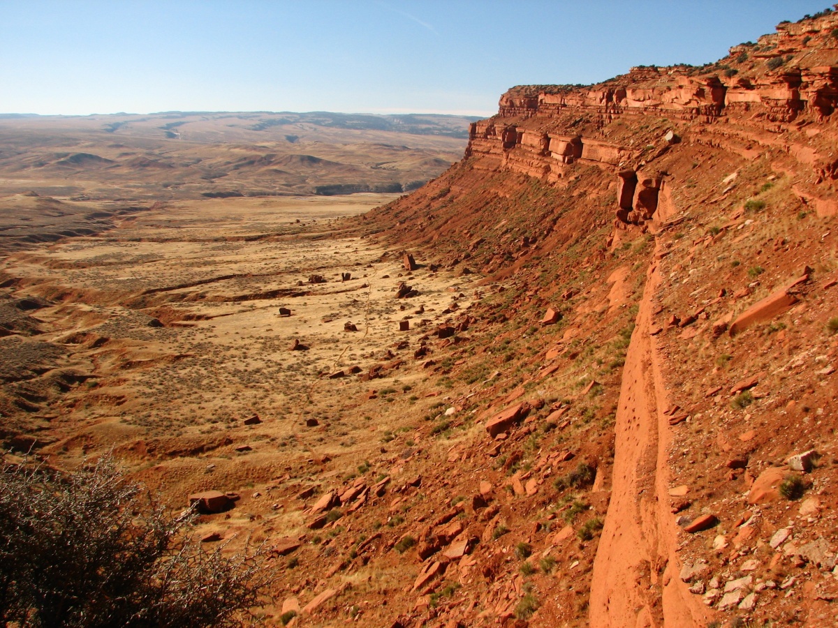A red stand stone wall lines a barren dessert.