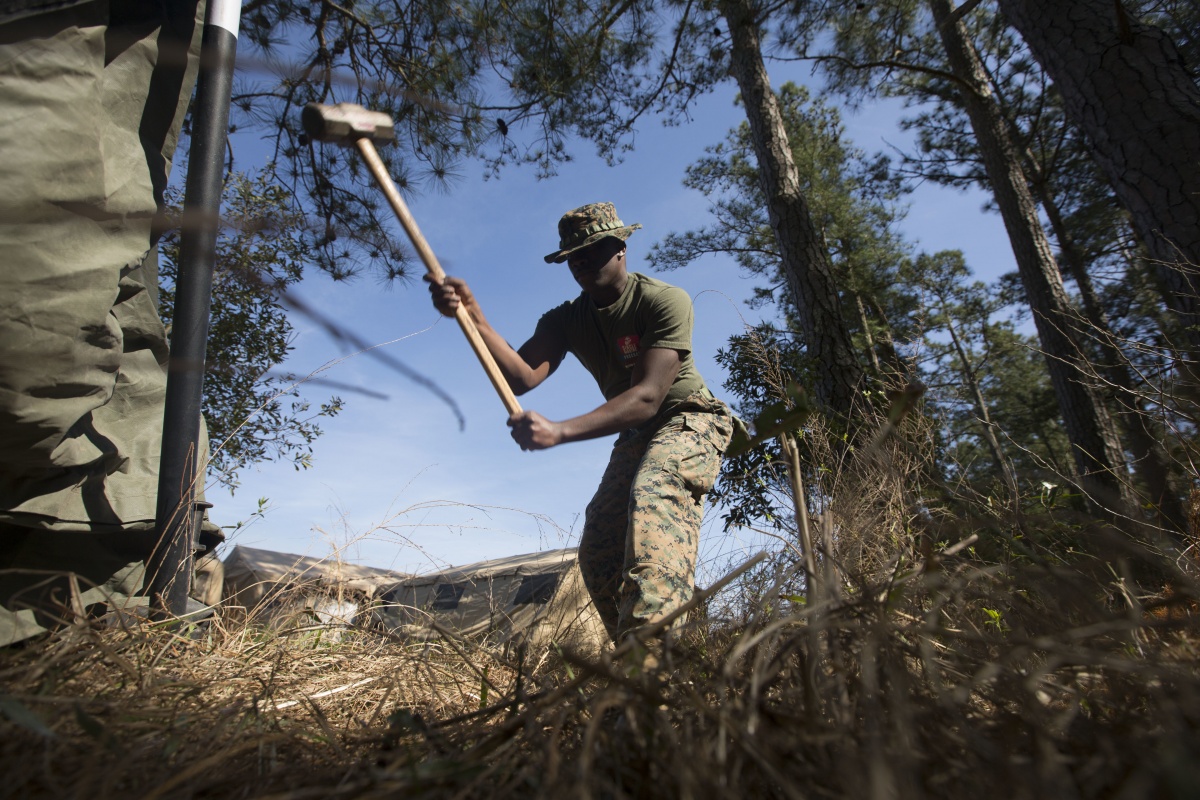 A U.S. Army Corporal hammers a tent stake into the ground.