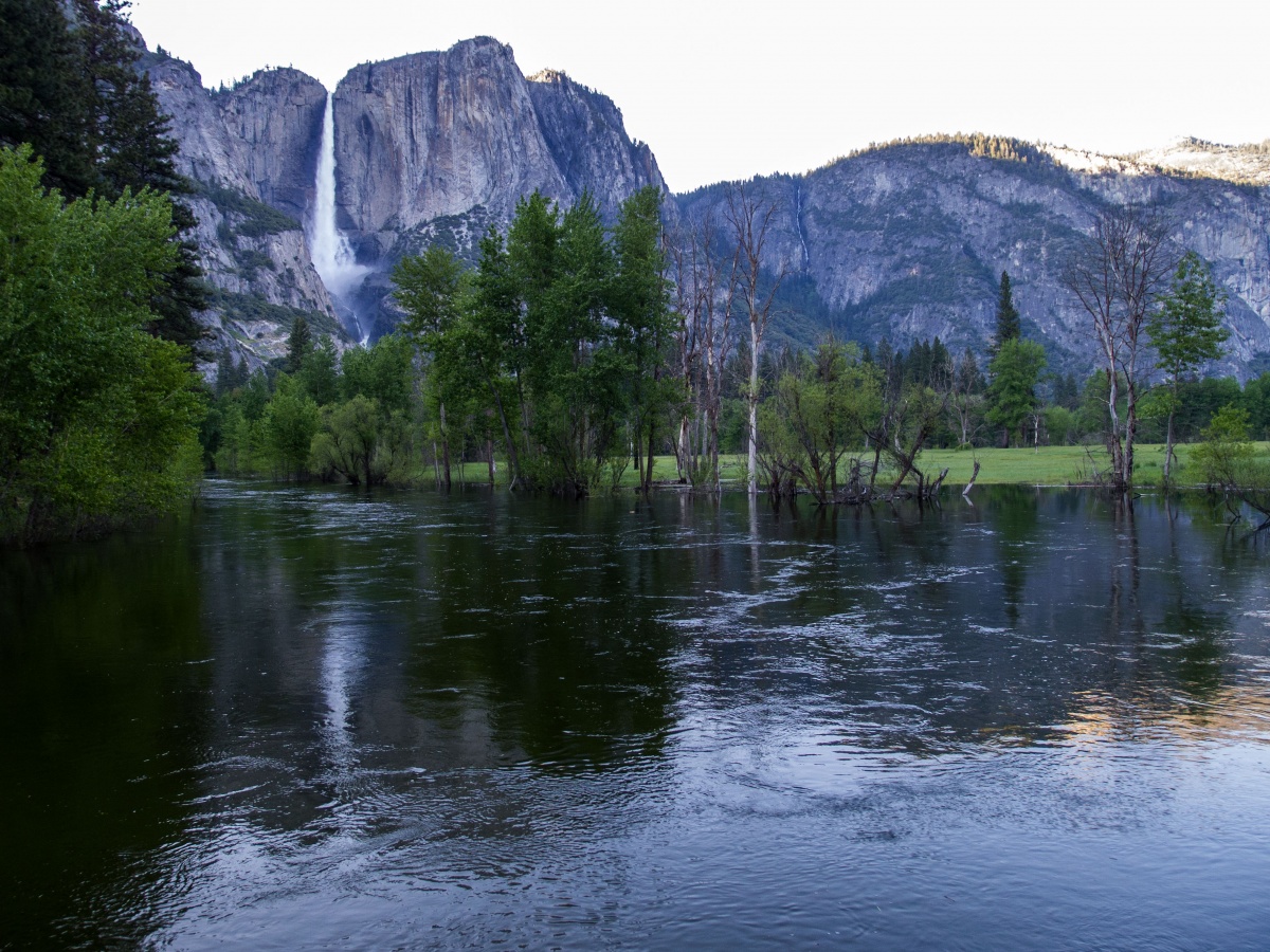 Mountains tower over the Merced River during sunrise. 