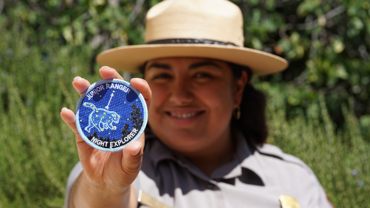 Park Ranger Holding up a Junior Ranger Patch