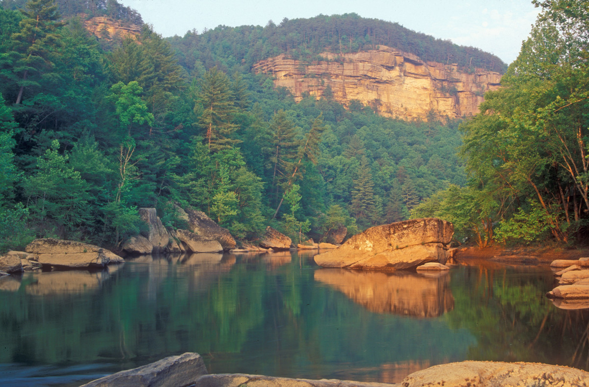 Trees and cliffs are reflected on the surface of a river