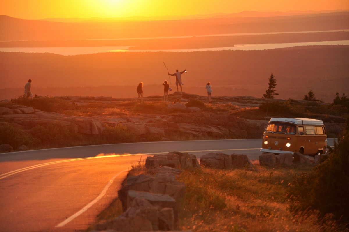 People standing on small rocks by Park Loop Road at sunset