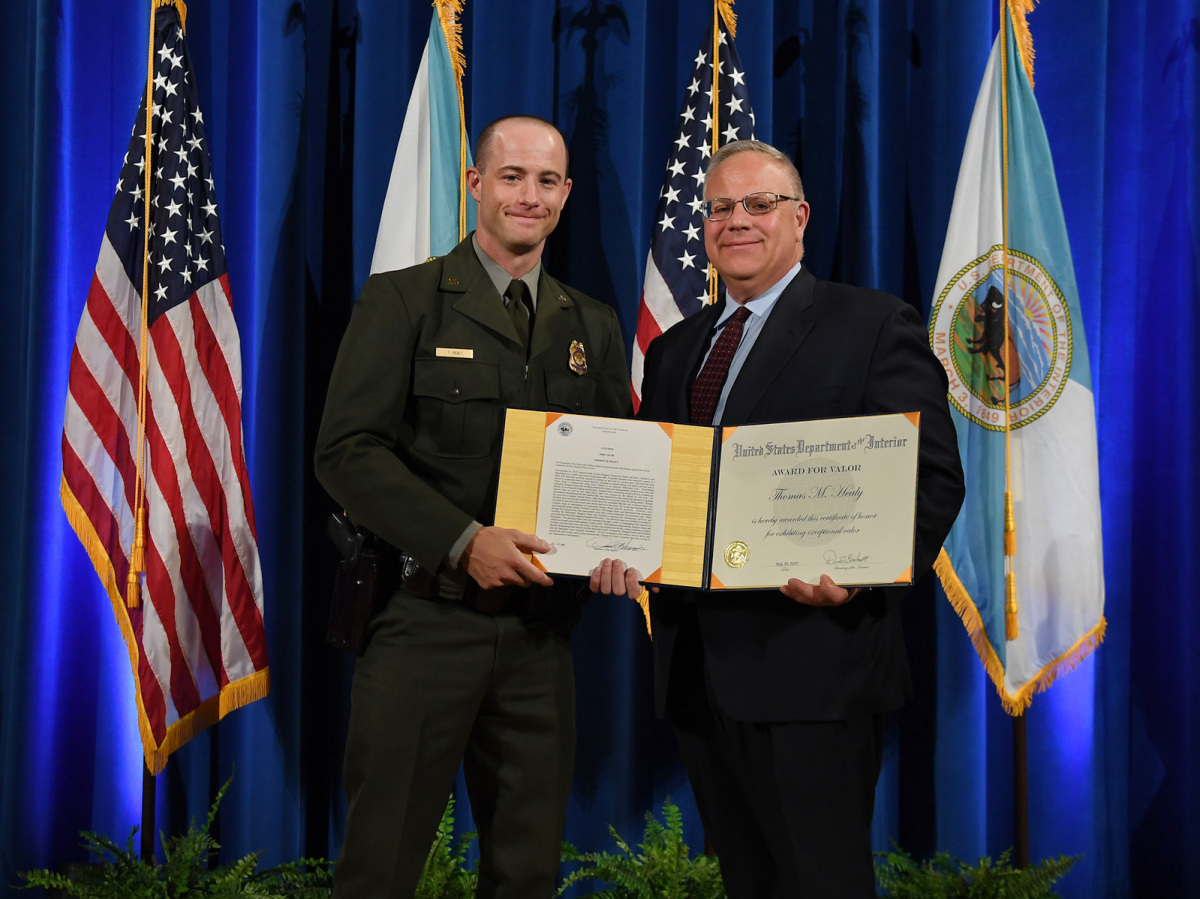 A white man in a ranger uniform receiving a certificate from a white man in a suit.
