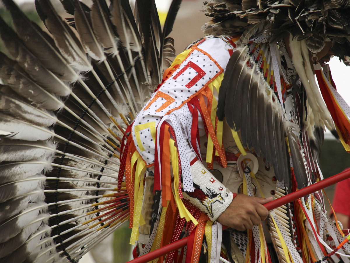 Native cultural dancer wearing red, orange, yellow, and feathers