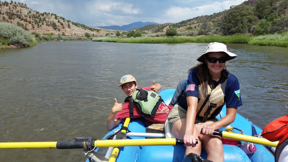 Two volunteers float down the river in a raft.