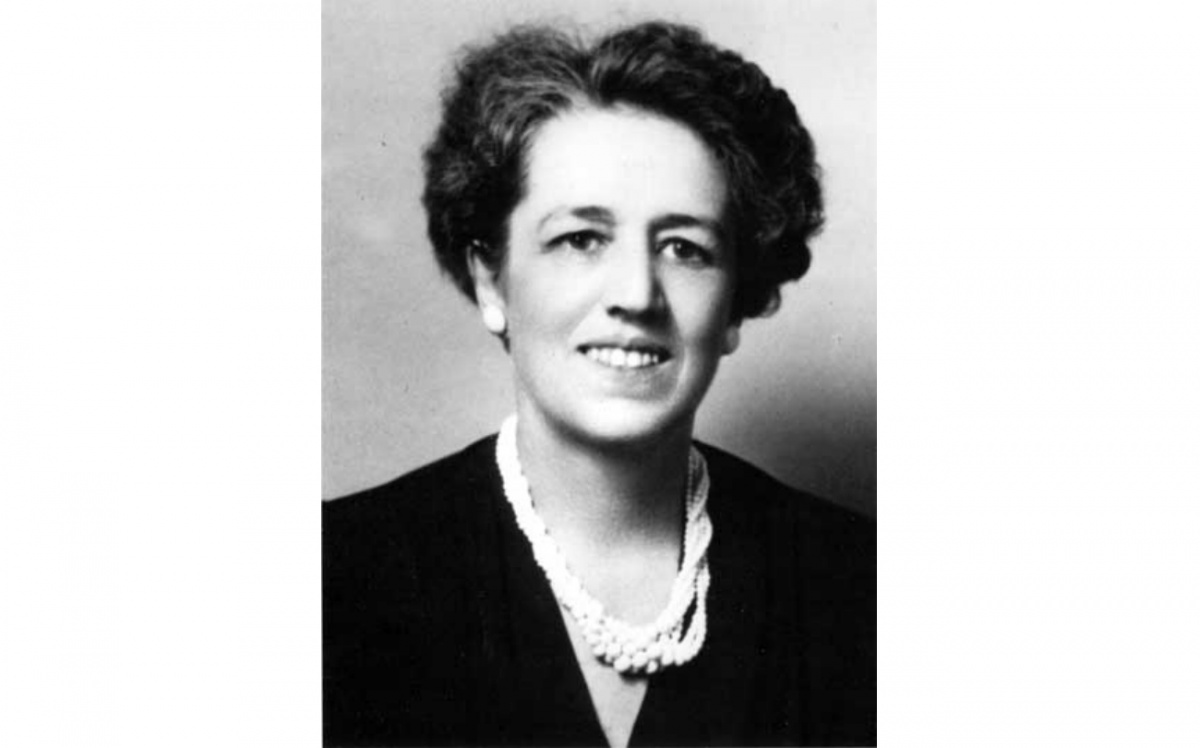 A black and white head shot of a woman, Gertrude S. Cooper, smiling and wearing a black top and white necklace.