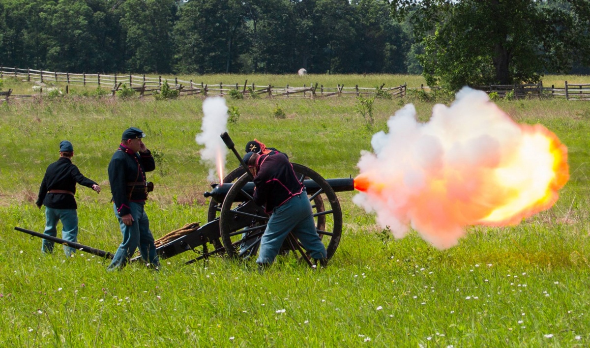 Four volunteers dressed as union soldiers fire a cannon in the middle of the field.