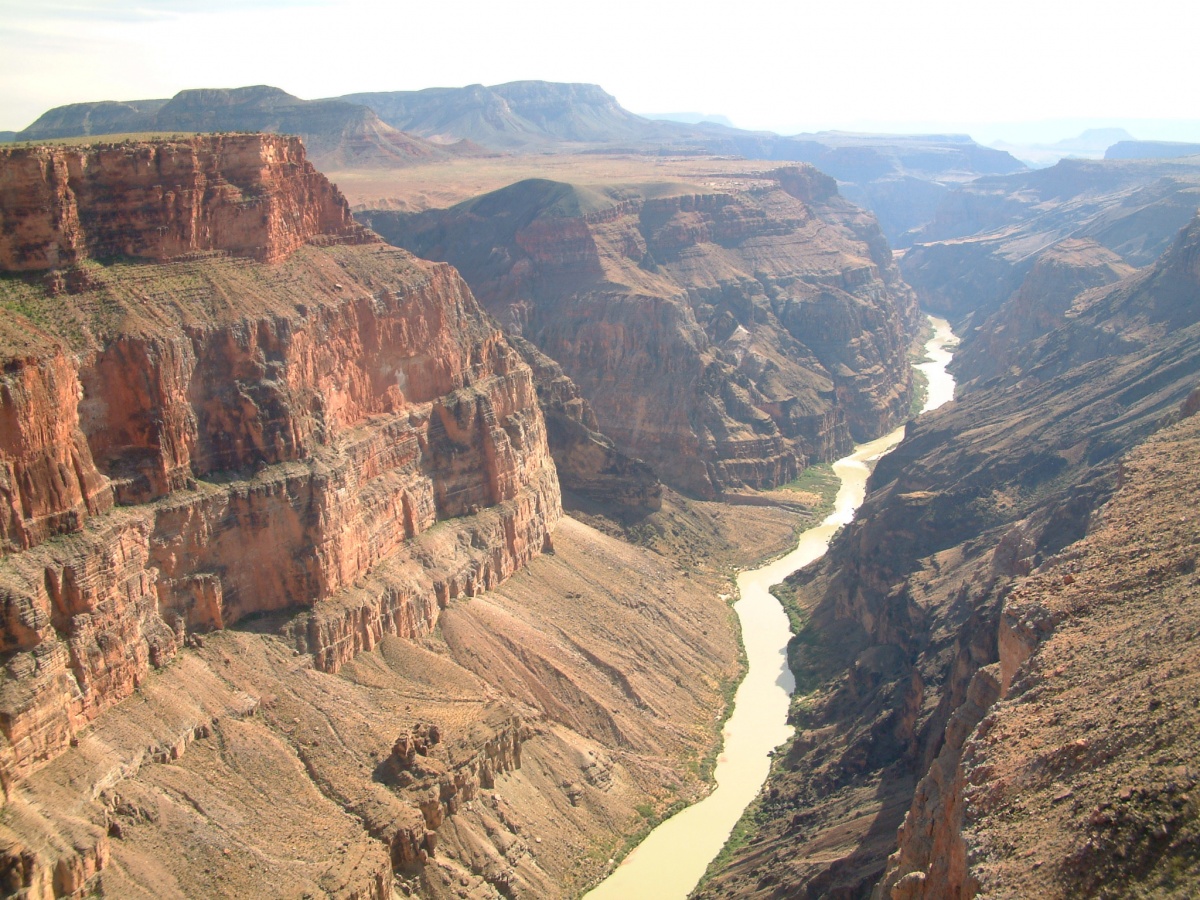 Photo of large orange and red canyons, a single long stream running between them 
