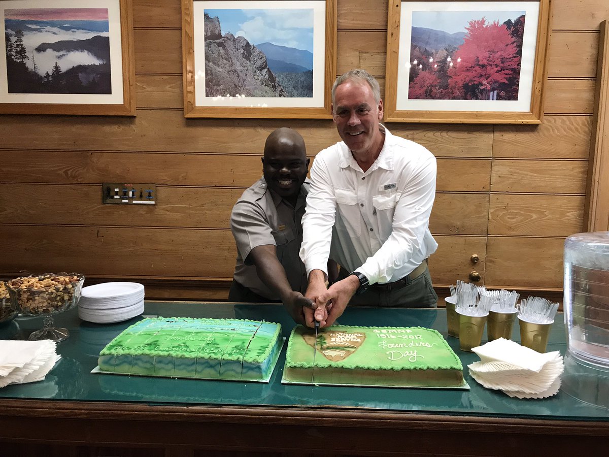 two man cut a cake together