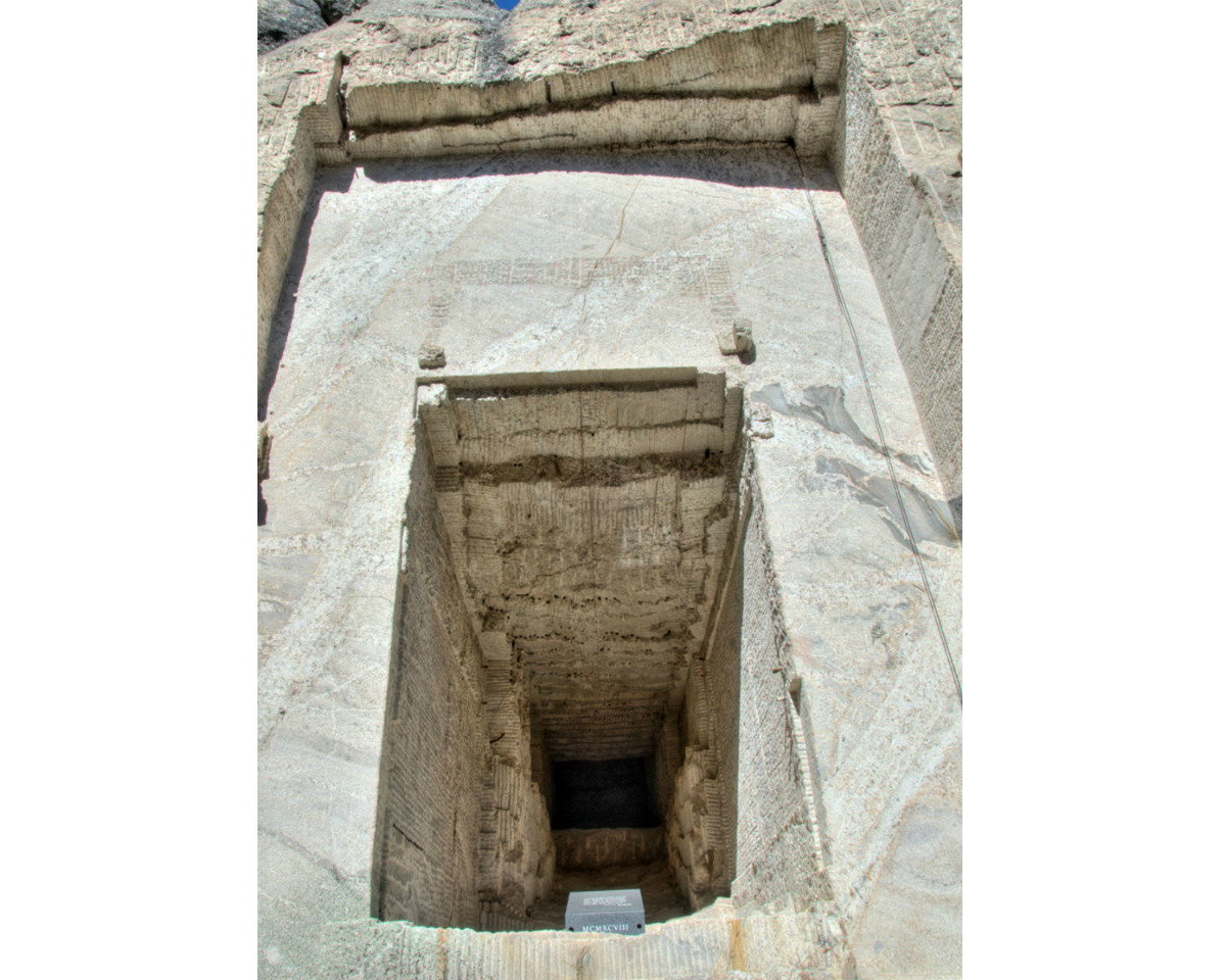 A tall open tunnel is cut into a flat stone wall.