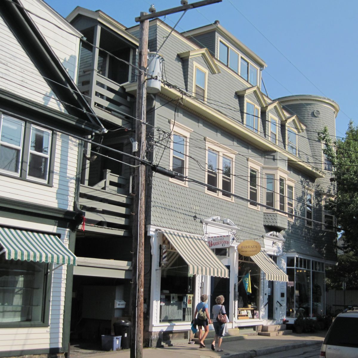 A green building stands as part of a row of buildings and houses.