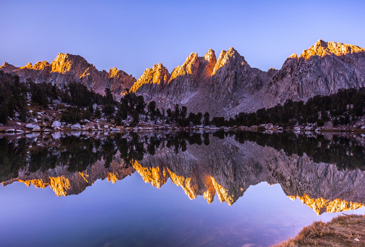 Purple skies over rugged mountains reflected in a lake