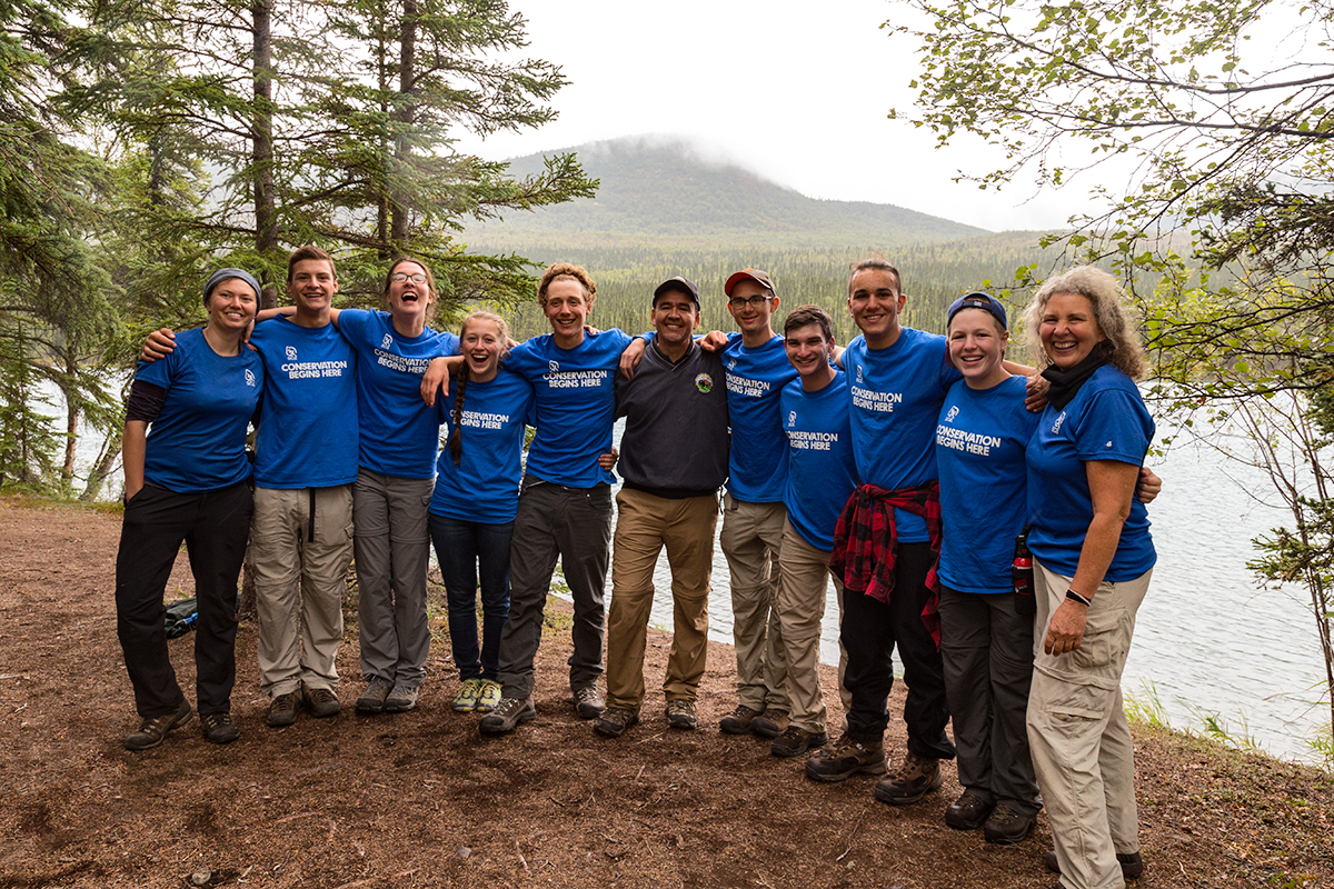 Deputy Secretary Connor poses with a group of students in front of a lake.