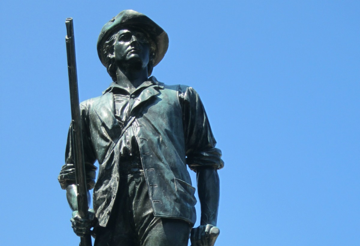 Statue of minute man with blue sky in background.