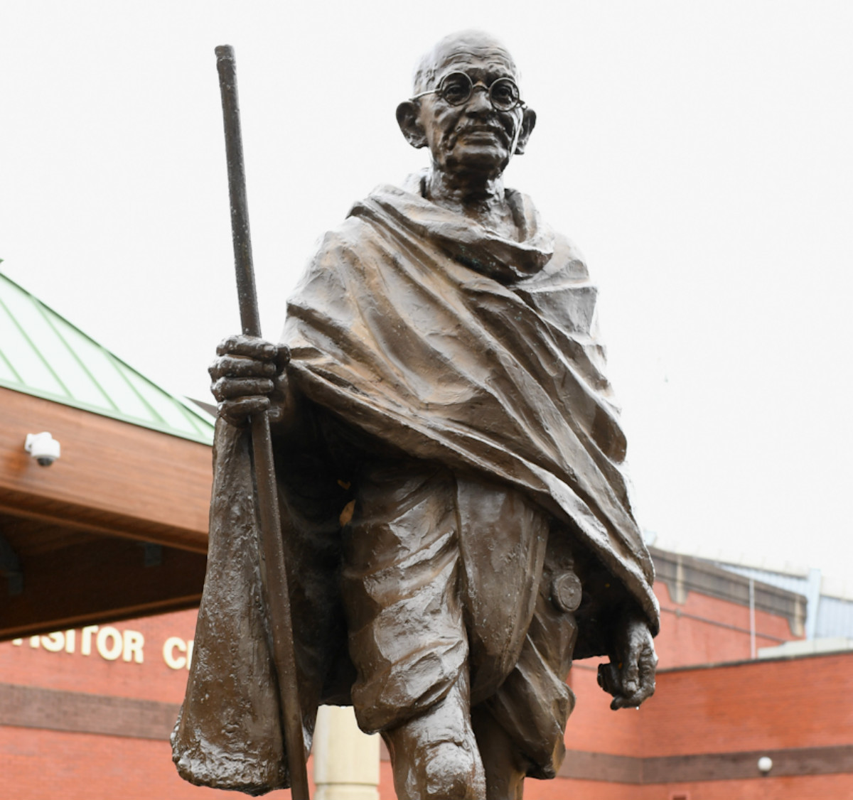 A statue of Gandhi - a short, bald man wearing glasses and carrying a walking stick.