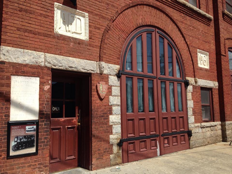 A red brick fire house has large doors on its front.