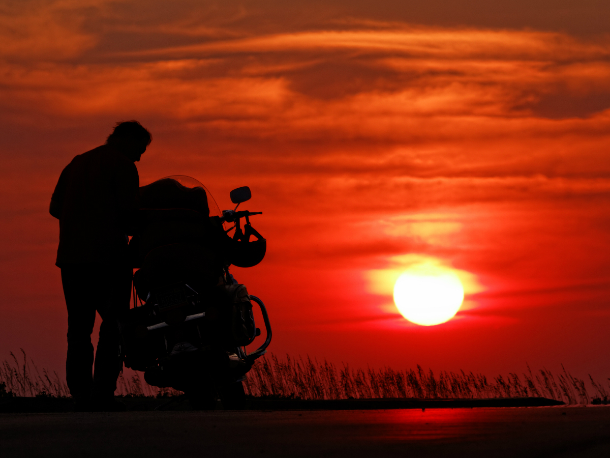 Man with a motorcycle at sunset