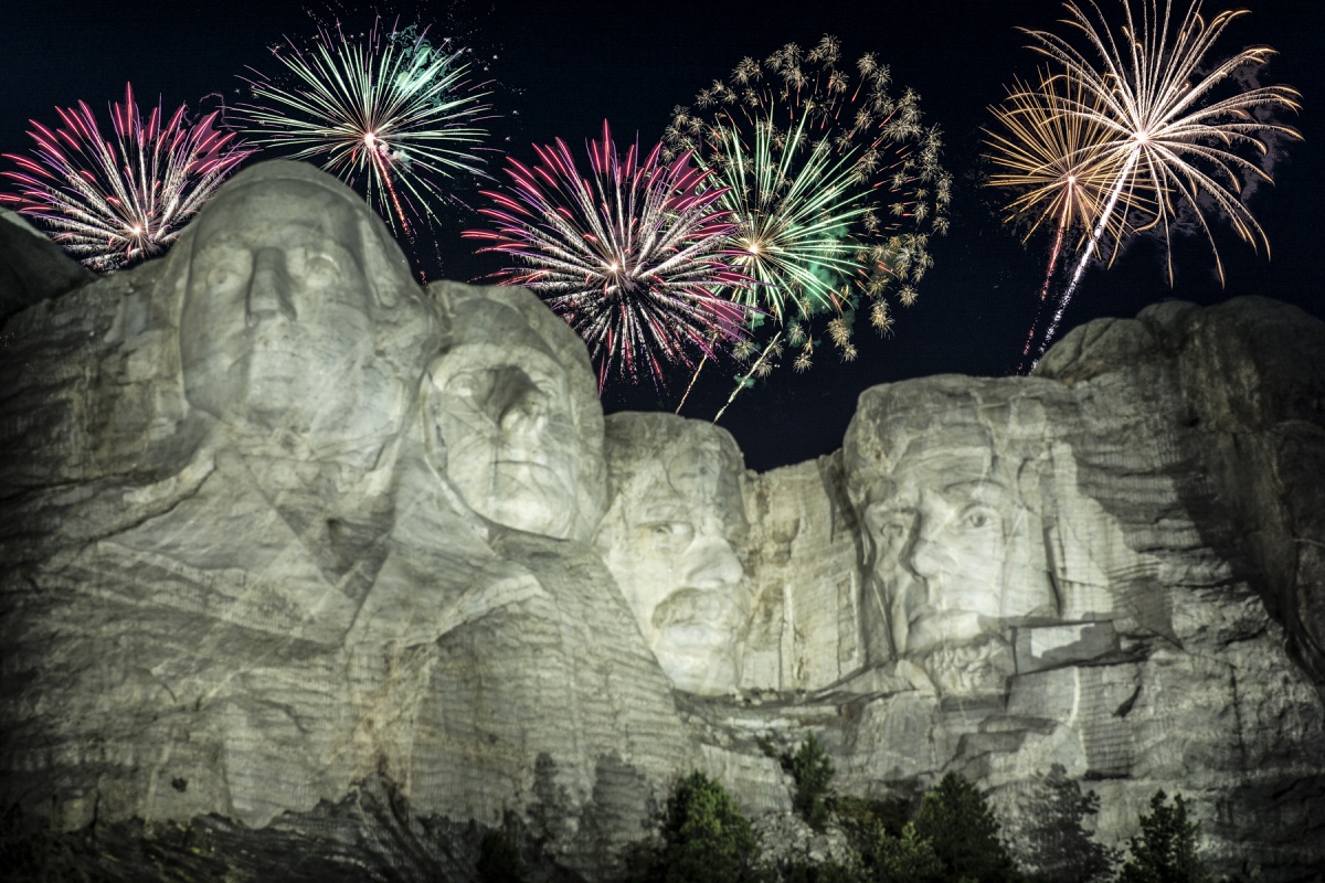 Fireworks explode in colors in the night sky over the four presidential sculptures.
