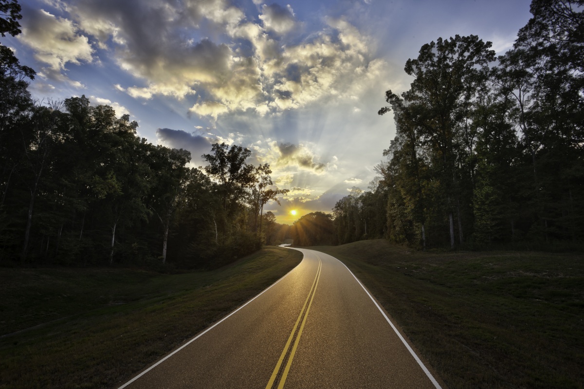 The Natchez Trace Parkway winding into the sunset with forest on each side of the road