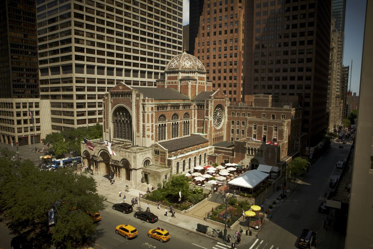 A small ornate church stands between looming skyscrapers.