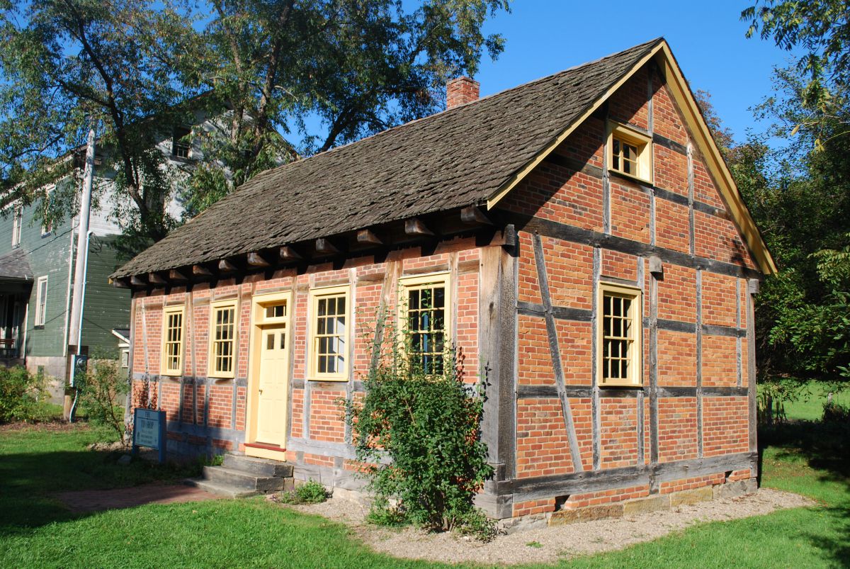 A small brick building stands alone surrounded by light green grass.