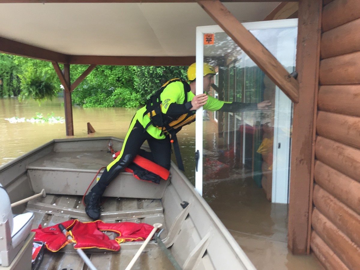 Man on boat opens door to flooded house.