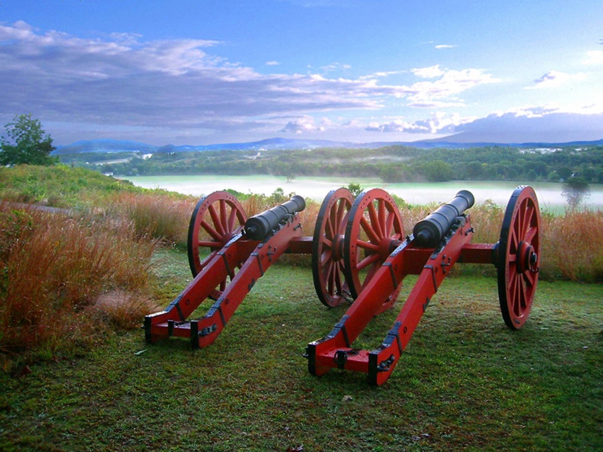 Red canyons on ground with lake and blue sky in background. 