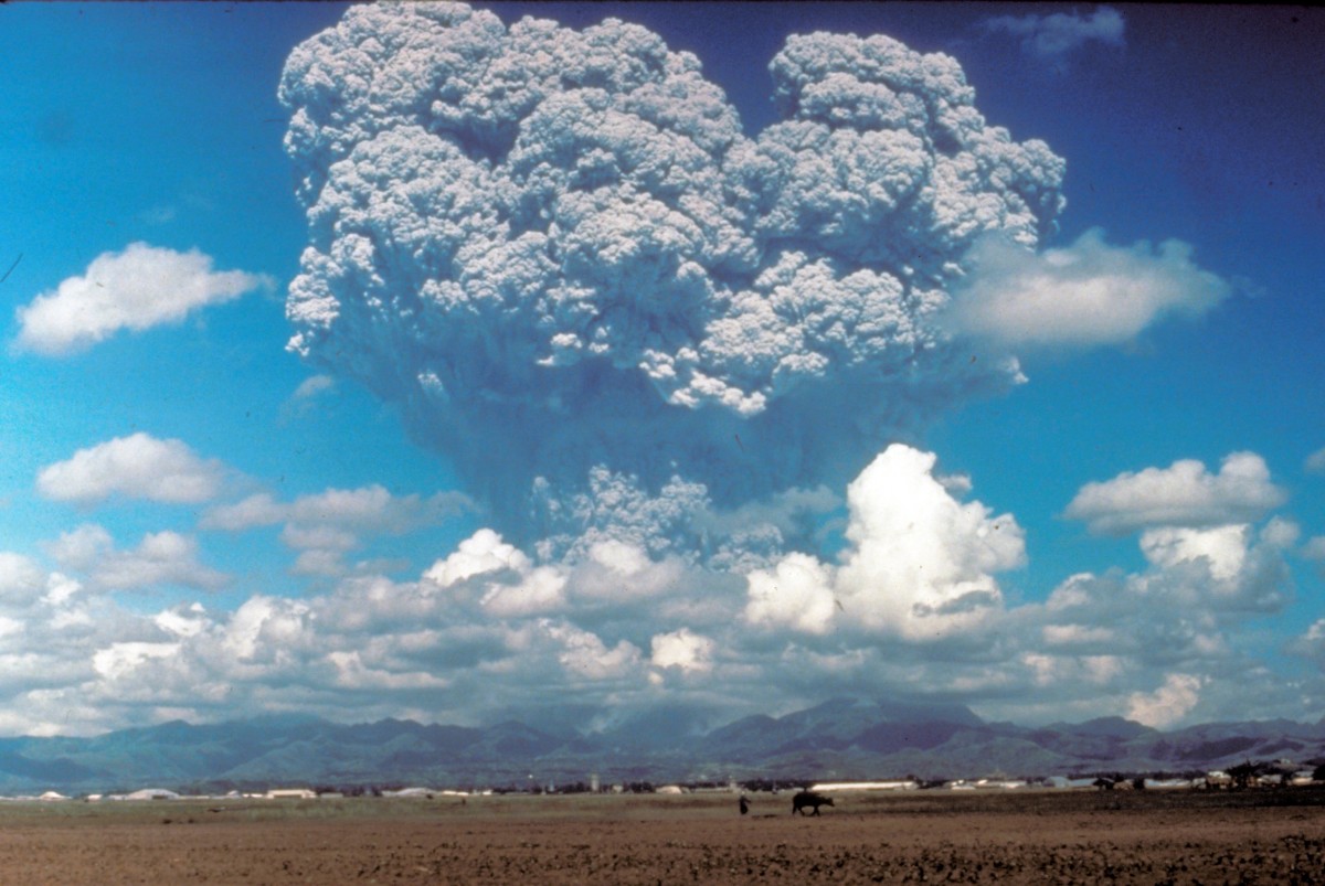 Volcano erupts in blue sky.