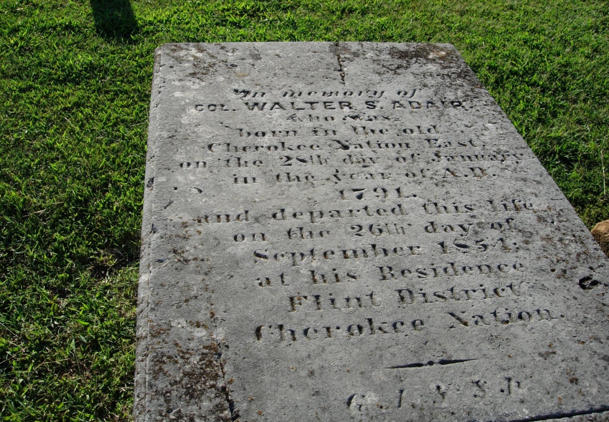 A grave marker lays flat on the grass