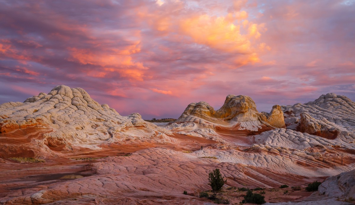 Unique rock formations jut up from the barren, discolored and cracking landscape during a stunning desert sunset.