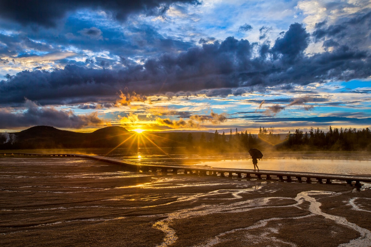 woman with an umbrella walks on a boardwalk at sunset rain storm