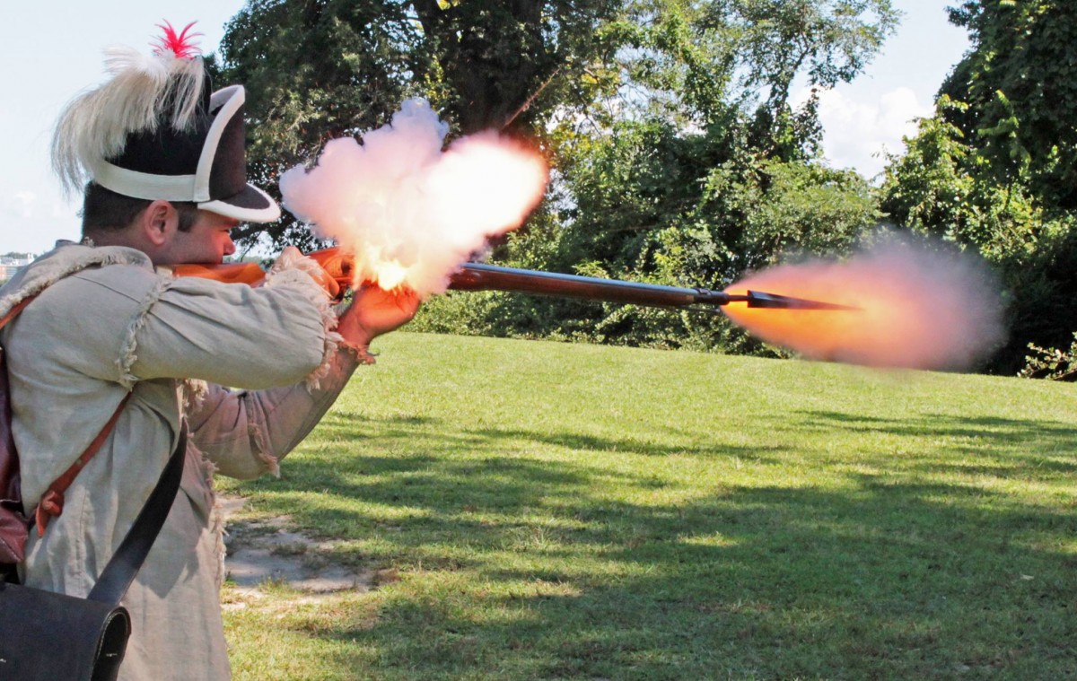 Reenactor fires musket.