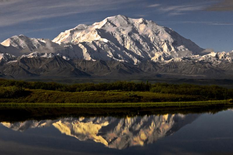 A snow covered Denali is reflected in a lake.