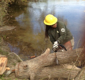 LaJuan Tucker chainsaws a fallen tree during flood restoration efforts at McKinney Falls State Park in Texas.